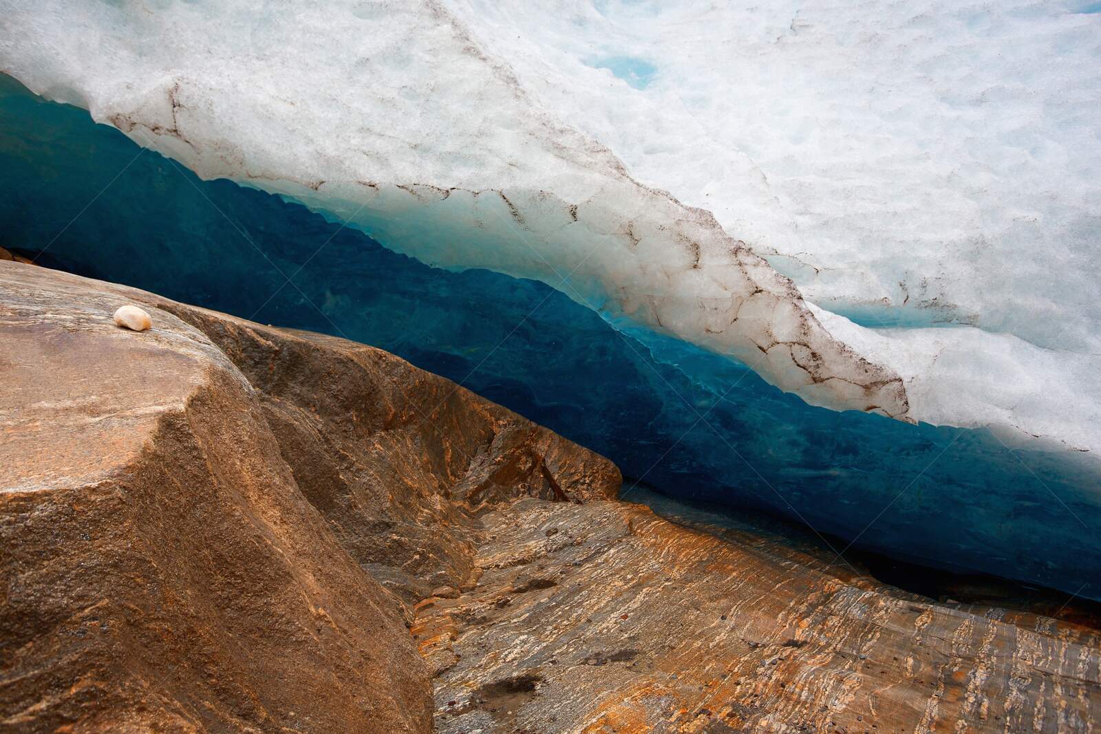 Close-up of blue glacier ice and brown rocky surface, Svartisen