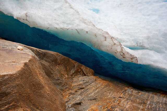 Close-up of blue glacier ice and brown rocky surface, Svartisen