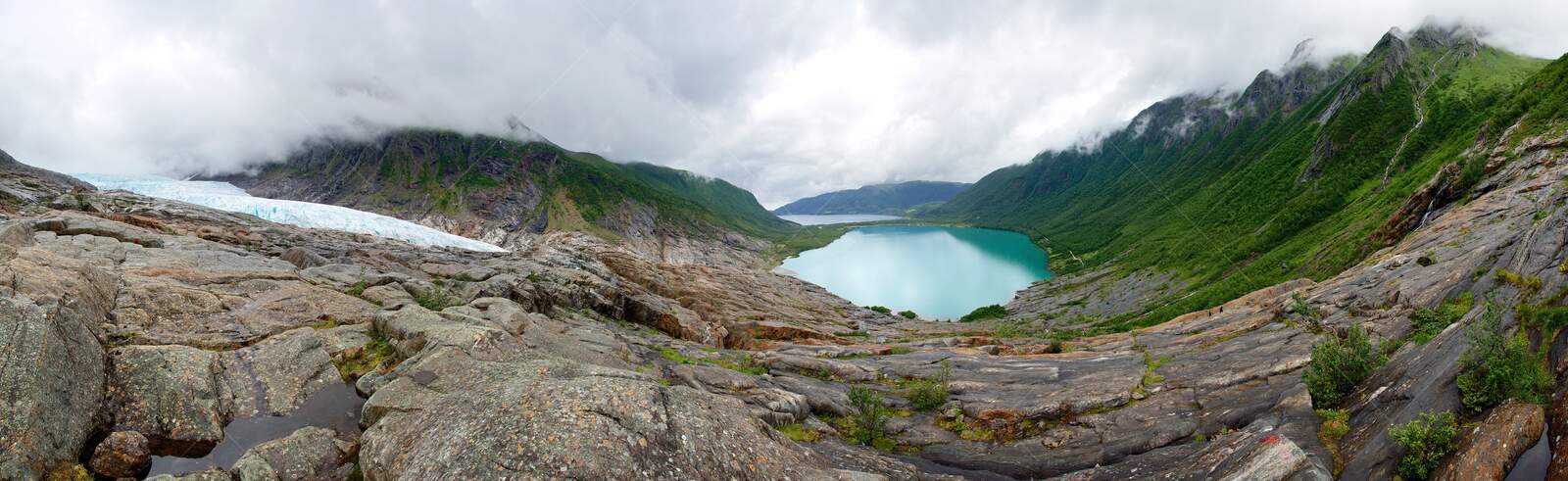 Svartisen glacier and turquoise lake surrounded by misty mountains