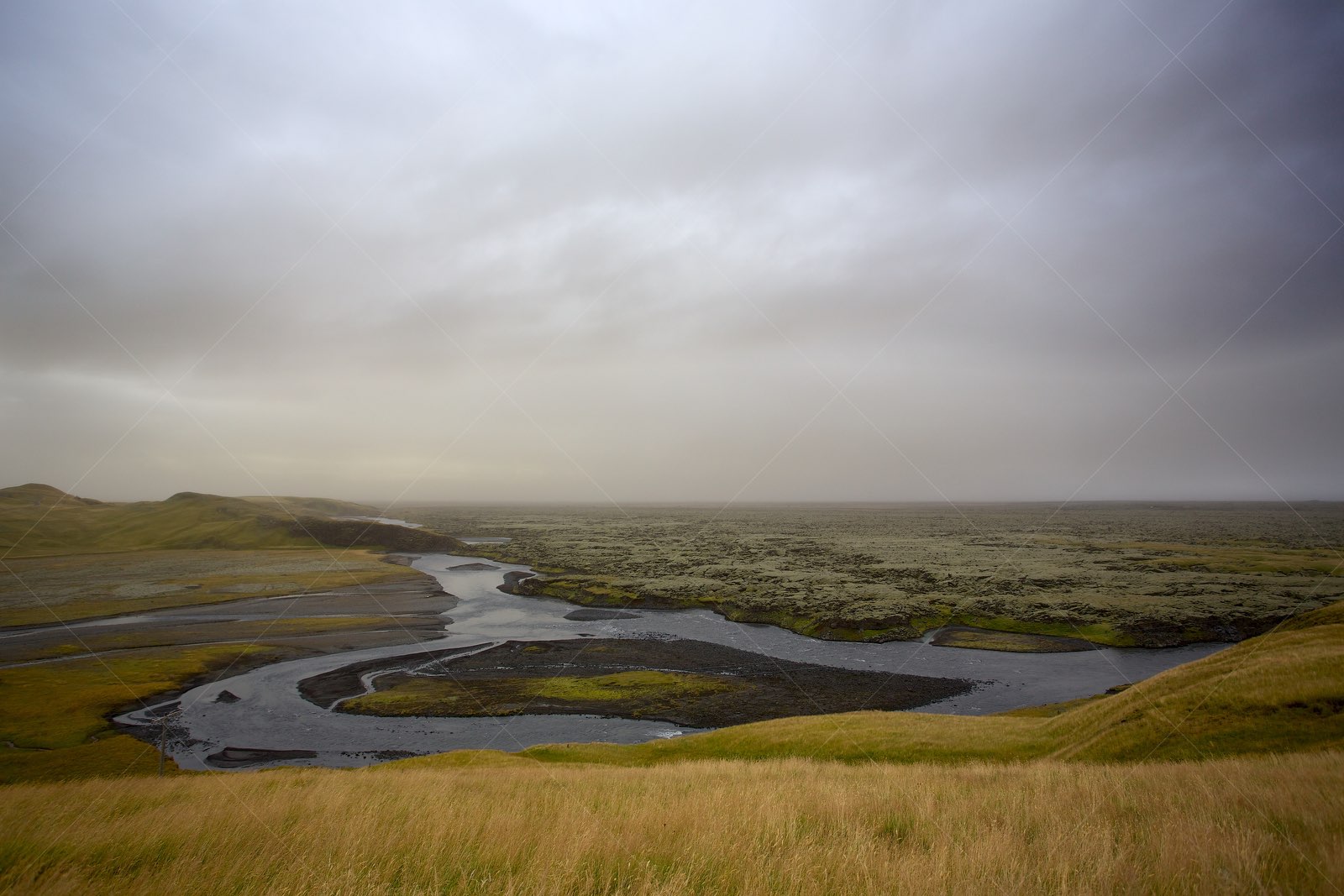 Misty river winding through mossy plains in South Iceland