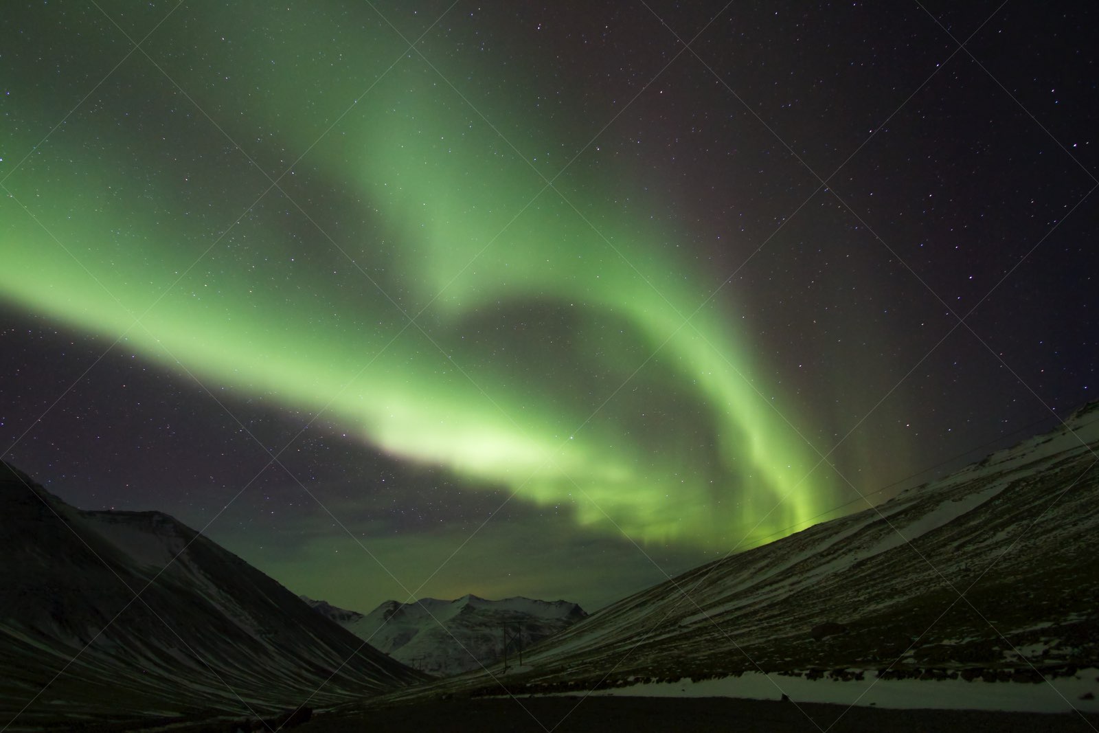 Aurora Borealis over snowy Icelandic mountains