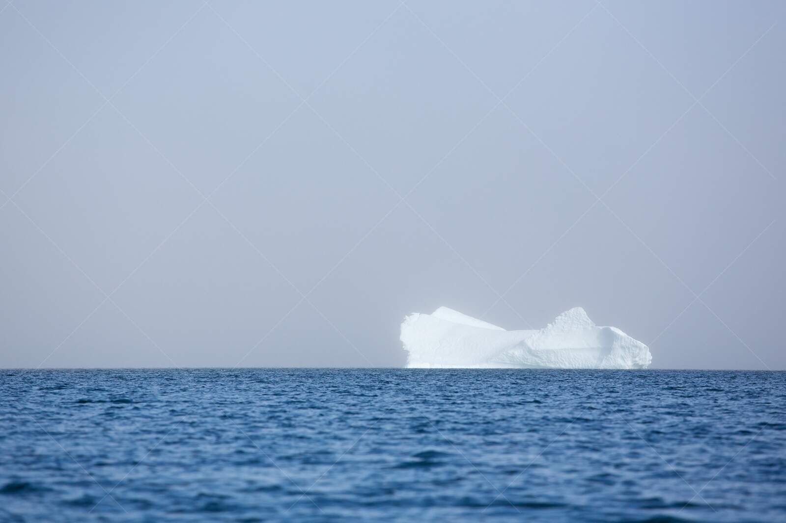 Large iceberg floating in calm ocean water