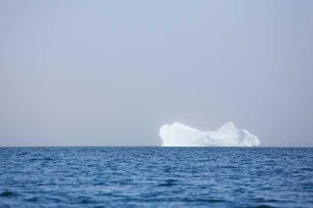 Large iceberg floating in calm ocean water