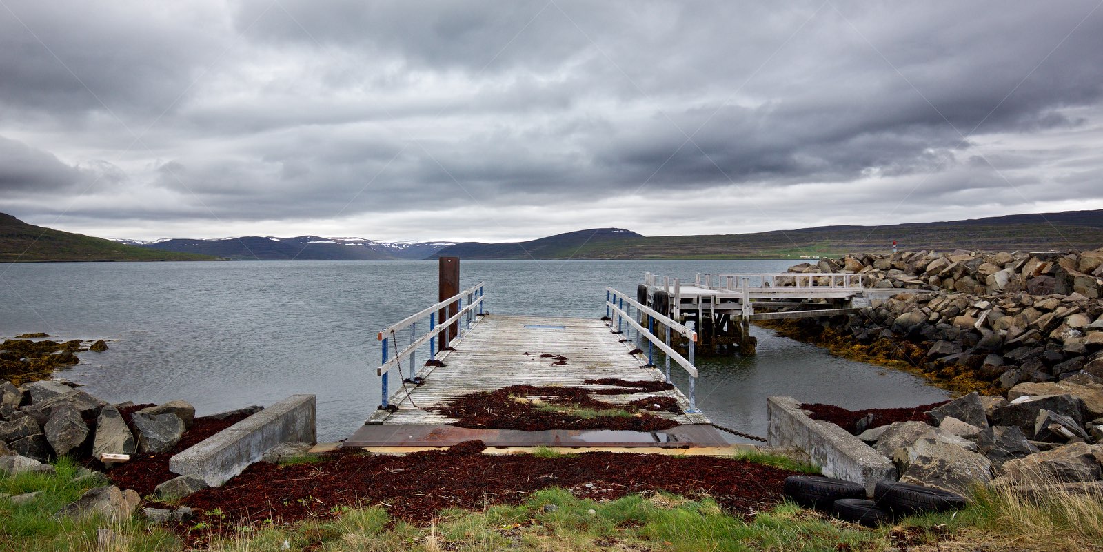 Wooden pier and rocky shore at Icelandic fjord