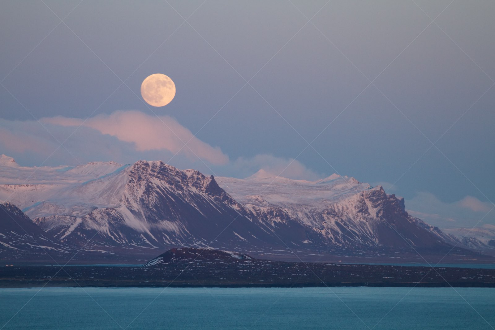 Full moon over snowy mountains in Snæfellsbær Iceland