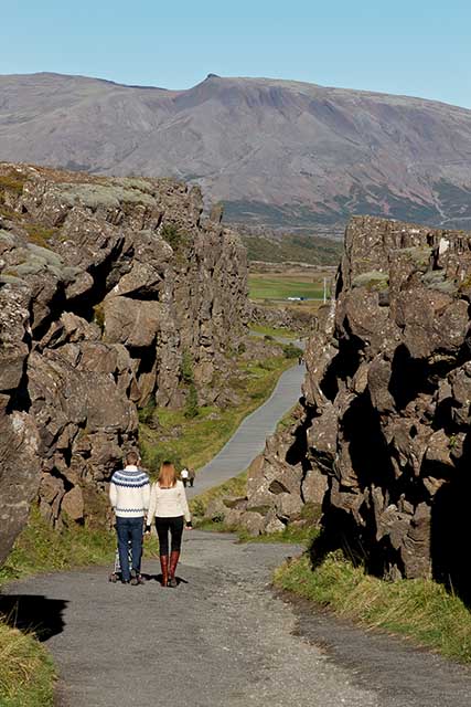 Couple walking along rocky path in Thingvellir Iceland