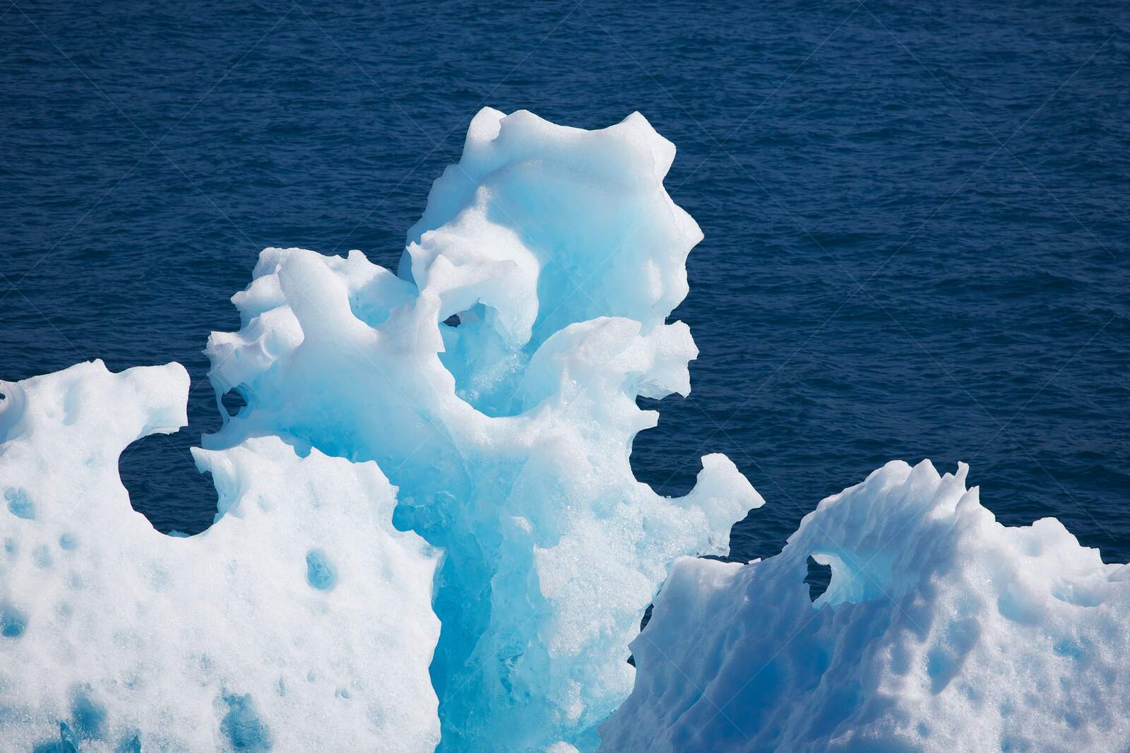 Close-up of sculpted blue iceberg in ocean