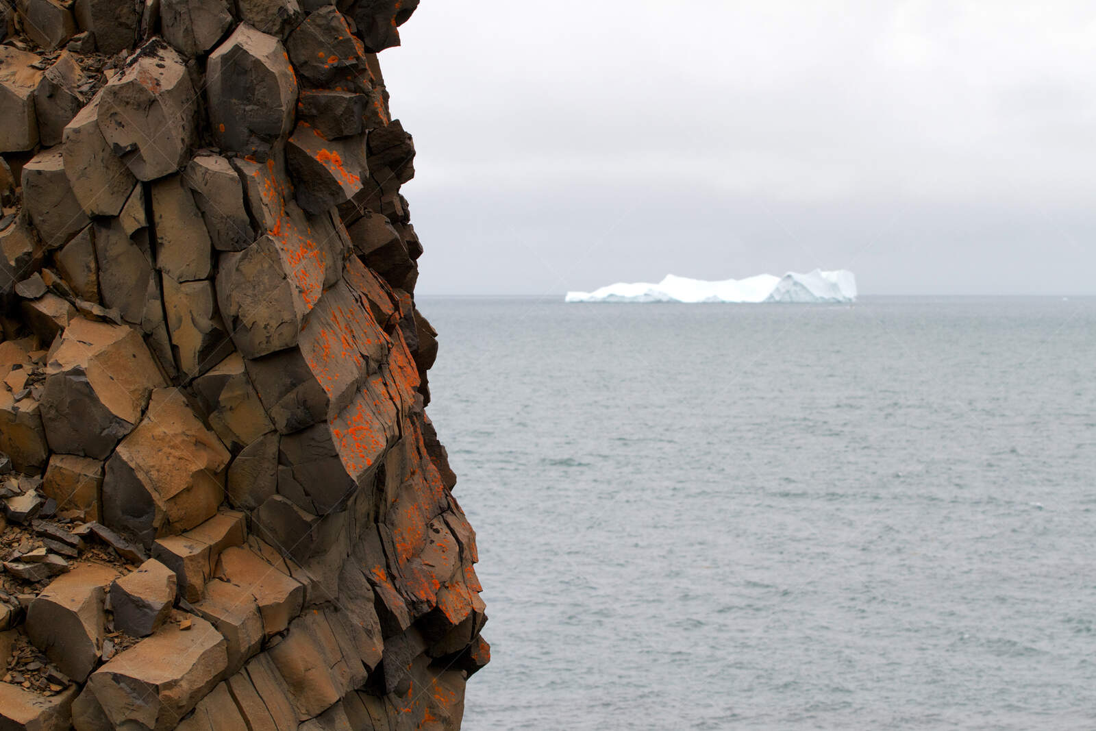 Basalt Sea Cliff and Distant Iceberg