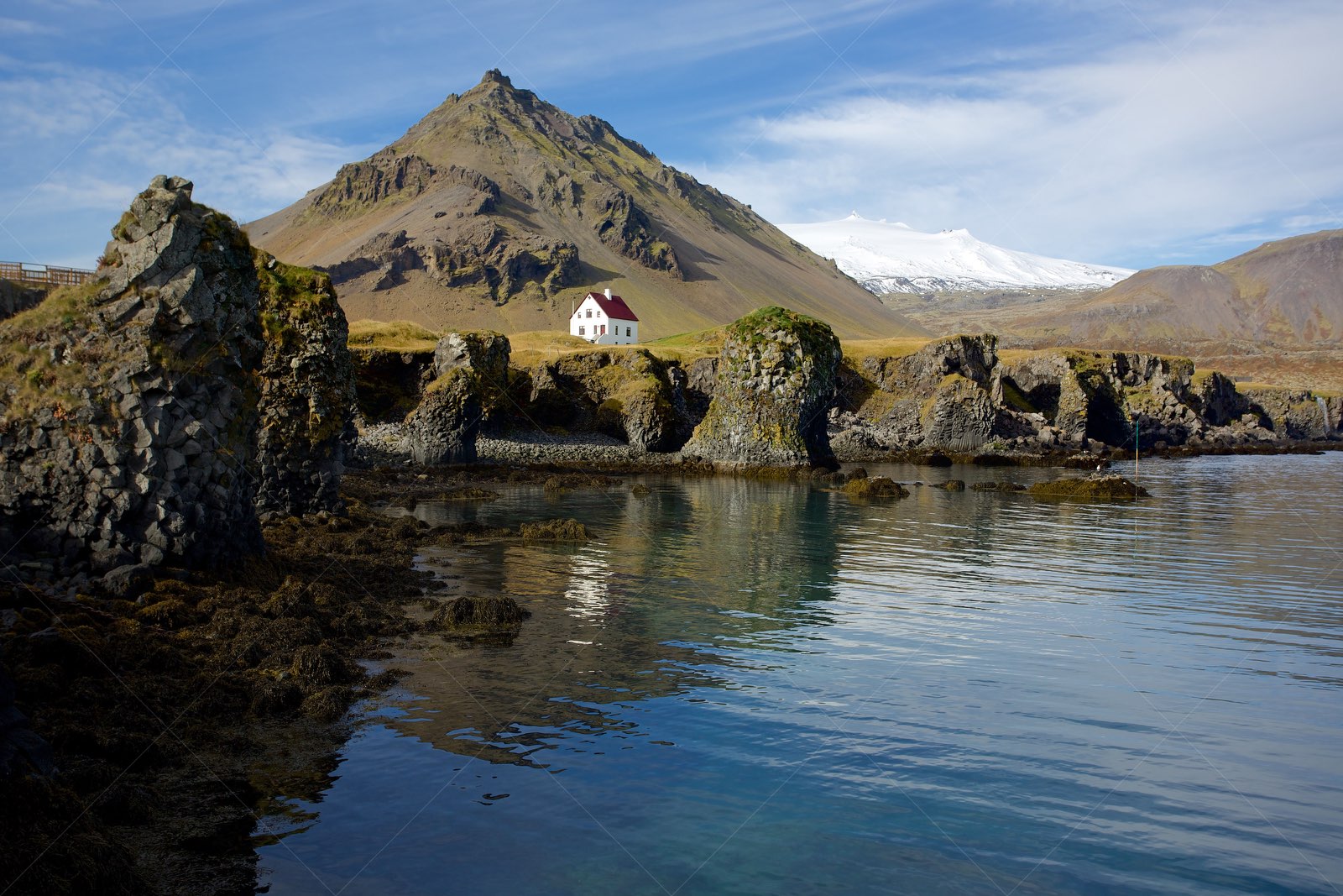 Arnarstapi coastal cliffs with mountain and house in Iceland