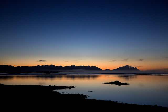 Sunset over calm waters with mountain silhouette in Iceland