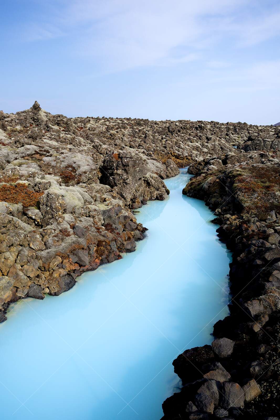 Milky blue geothermal water flowing through lava rocks