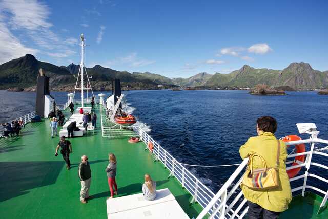 Cruise ship sailing near rocky green mountains in clear weather, Norway