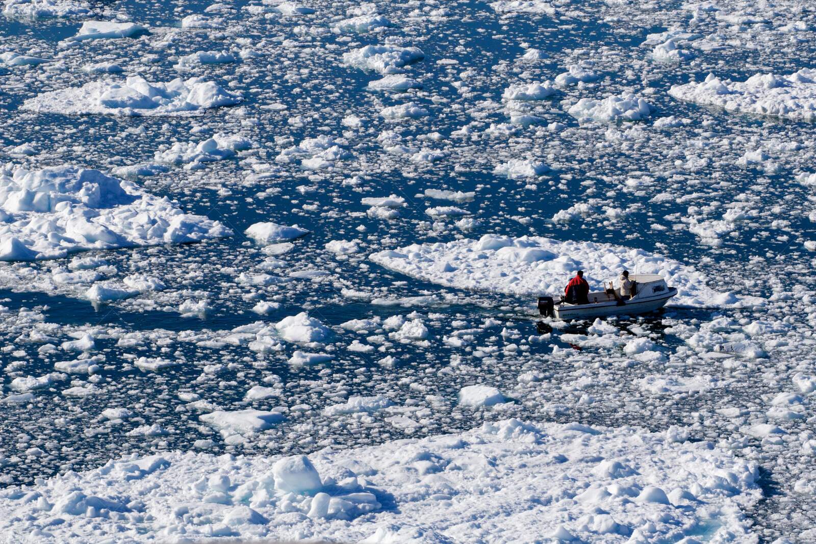 Fishermen navigating iceberg-filled fjord in Ilulissat Greenland