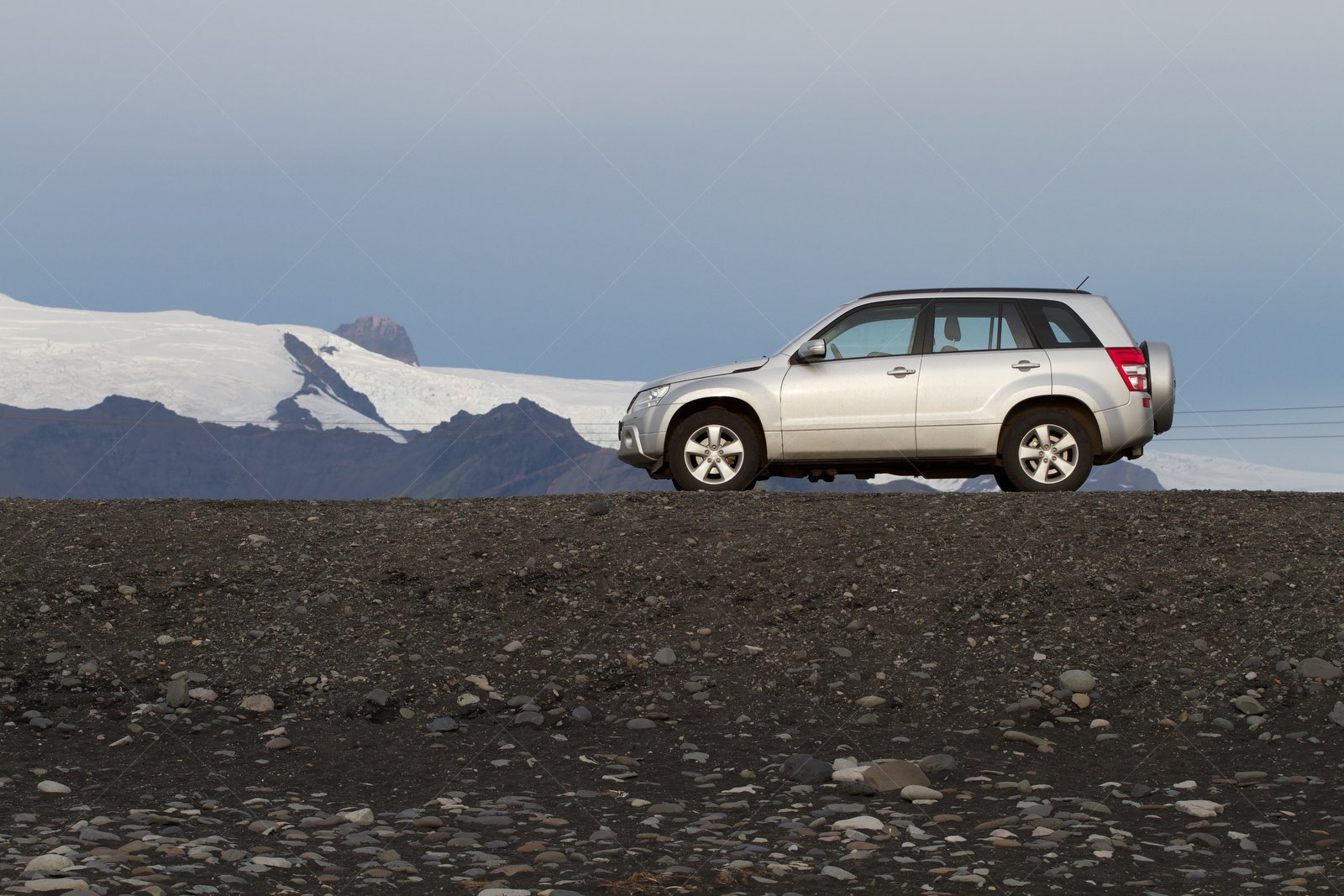 Silver SUV parked near glacier mountain