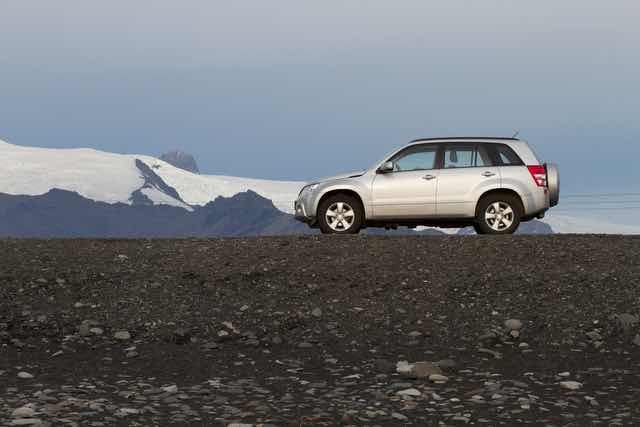 Silver SUV parked near glacier mountain